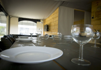 Set dining table with plates and glasses inside a safari tent villa at Holiday Park Duinhoeve, Netherlands.