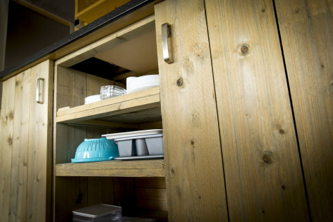 Armadio in legno con scaffali aperti che mostra stoviglie in una tenda villa presso Holiday Park Duinhoeve.