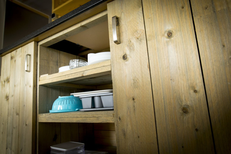 Armoire en bois avec étagères ouvertes montrant de la vaisselle dans une tente villa au Holiday Park Duinhoeve.