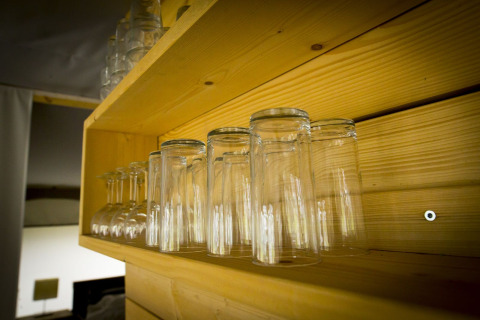 Upside-down glasses on a wooden shelf inside a safari tent at Holiday Park Duinhoeve, Netherlands.