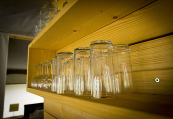 Upside-down glasses on a wooden shelf inside a safari tent at Holiday Park Duinhoeve, Netherlands.