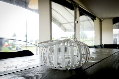 Indoor photo of a glass lantern with a white frame on a wooden table in a safari tent at Holiday Park Duinhoeve.