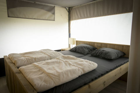 Vista interna di un letto accogliente nella tenda safari Tent Villa all’Holiday Park Duinhoeve, Paesi Bassi.