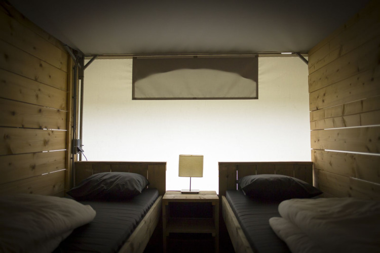 Vue intérieure d'une tente safari villa avec deux lits simples et des murs en bois au Holiday Park Duinhoeve, Pays-Bas.