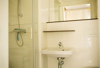 Bathroom inside the Tent Villa safari tent at Holiday Park Duinhoeve, Netherlands, featuring a shower and sink.