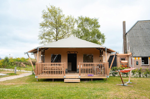 Safari-Zelt Villatent Cottage im Vakantiepark De Nollen, Niederlande, mit Veranda und Hängematte davor.