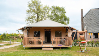 Safari-Zelt Villatent Cottage im Vakantiepark De Nollen, Niederlande, mit Veranda und Hängematte davor.