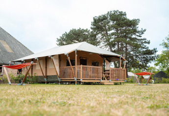 Safari tent Villatent Cottage at Vakantiepark De Nollen in the Netherlands, with hammocks on the lawn.