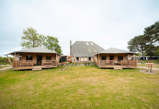 Tenda safari Villatent Cottage al Vakantiepark De Nollen nei Paesi Bassi, con prato verde davanti.