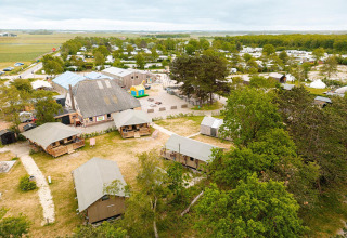 Vista aérea de tiendas safari y edificio principal en Vakantiepark De Nollen, rodeado de vegetación en Holanda.