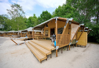 Safari tent Villatent Cottage at Vakantiepark Sallandshoeve in the Netherlands with a wooden deck and trees.