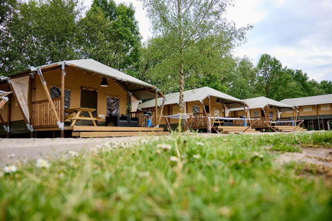 Safari tents Villatent Cottage lined up at Vakantiepark Sallandshoeve, surrounded by greenery in the Netherlands.