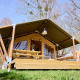 Safari-Zelt Villatent Compact mit überdachter Holzterrasse, Sitzbank und Natur im Hintergrund.