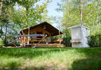 Safari-Zelt Villatent Compact + Sanitär im Recreatiepark de Lucht, Niederlande, mit viel Grün drumherum.