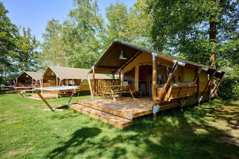 Tente safari Villatent Compact + sanitaire au Recreatiepark de Lucht, Pays-Bas, entourée d’arbres verts.