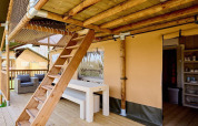 Terraza de madera con escalera y zona de picnic en la tienda Villatent Ranger en Camping 't Geuldal, Países Bajos.