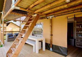 Terraza de madera con escalera y zona de picnic en la tienda Villatent Ranger en Camping 't Geuldal, Países Bajos.