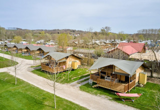 Buitenaanzicht van Villatent Ranger safaritenten op Camping 't Geuldal in Nederland, met veranda’s en hangmatten.