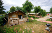 Tienda safari Villatent Nomad en Camping Le Coin Tranquille, Francia, con terraza y zona de barbacoa al aire libre.