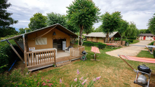 Tienda safari Villatent Nomad en Camping Le Coin Tranquille, Francia, con terraza y zona de barbacoa al aire libre.