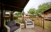 View from the deck of a Villatent Nomad at Camping Le Coin Tranquille, France, with outdoor chairs and greenery.