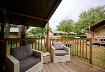 View from the deck of a Villatent Nomad at Camping Le Coin Tranquille, France, with outdoor chairs and greenery.