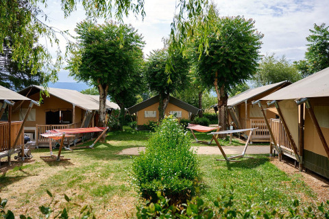 Tende safari al Villatent Nomad presso Camping Le Coin Tranquille in Francia, circondate da alberi e prato.