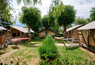 Safari-telte ved Villatent Nomad på Camping Le Coin Tranquille i Frankrig, omgivet af træer og græsplæner.