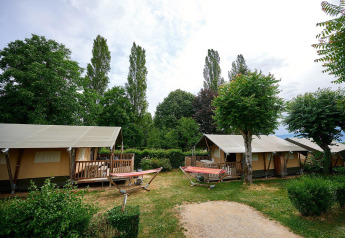 Tiendas safari con terrazas y hamacas en Camping Le Coin Tranquille en Francia, rodeadas de árboles.