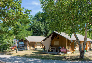 Tenda safari Villatent Nomad al Camping Le Lac Bleu in Francia, circondata da alberi e attrezzature da campeggio.