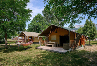 Tiendas safari con terrazas y hamacas en Camping Le Lac Bleu, Francia, rodeadas de árboles y naturaleza.