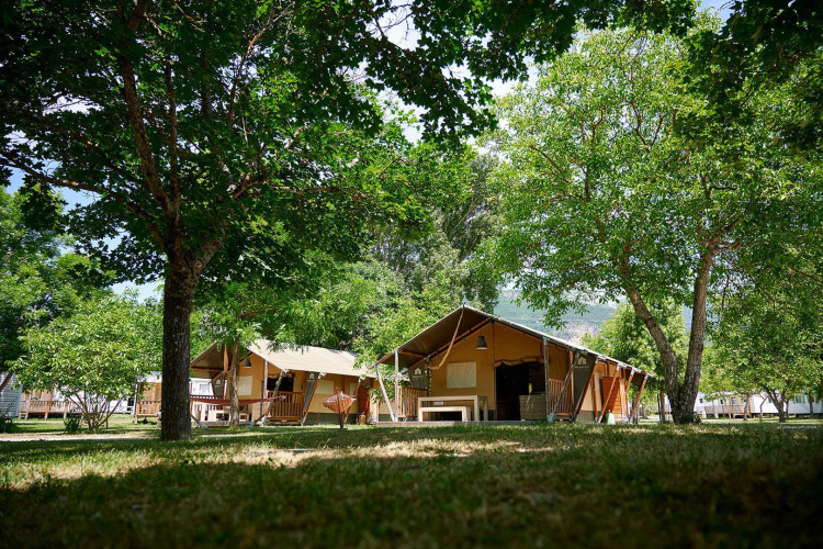 Tiendas de campaña safari en Villatent Nomad, Camping Le Lac Bleu, Francia, rodeadas de árboles verdes.