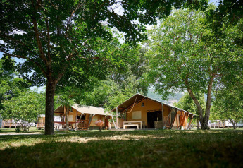 Tentes safari Villatent Nomad au Camping Le Lac Bleu en France, entourées d’arbres verts et de nature.