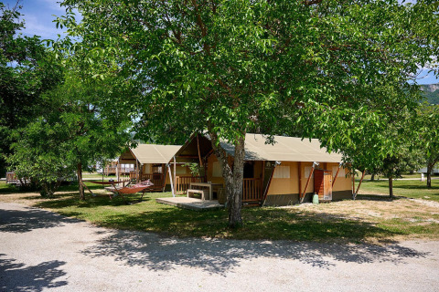 Safari tent Villatent Nomad at Camping Le Lac Bleu in France, set among green trees and peaceful nature.