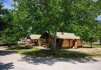 Tente safari Villatent Nomad au Camping Le Lac Bleu en France, entourée d'arbres et de verdure paisible.
