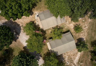 Vista aérea de dos tiendas safari Villatent Nomad en Camping Le Lac Bleu en Francia, rodeadas de vegetación.