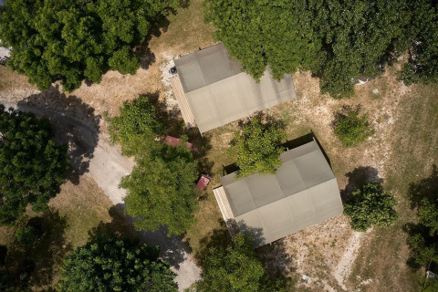 Luchtfoto van twee Villatent Nomad safaritenten bij Camping Le Lac Bleu in Frankrijk, tussen bomen.