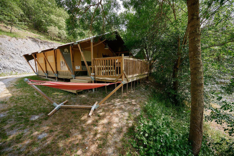 Safaritent Villatent Nomad op Camping Le Canigou in Frankrijk, met houten veranda en buitenhangmat.