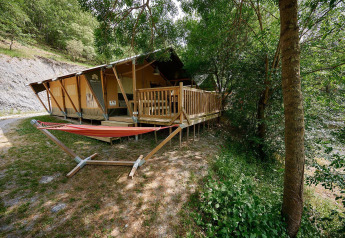 Tienda safari Villatent Nomad en Camping Le Canigou, Francia, con terraza de madera y hamaca exterior.