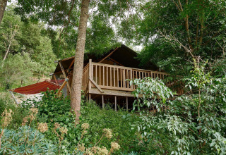 Tienda safari Villatent Nomad en Camping Le Canigou, Francia, rodeada de naturaleza y vegetación exuberante.