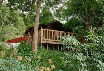 Tienda safari Villatent Nomad en Camping Le Canigou, Francia, rodeada de naturaleza y vegetación exuberante.