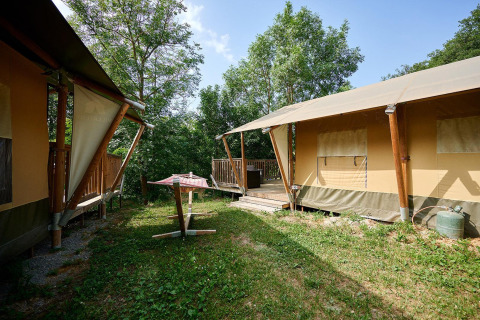 Safaritenten met houten terras tussen het groen op Camping Le Canigou in Frankrijk.