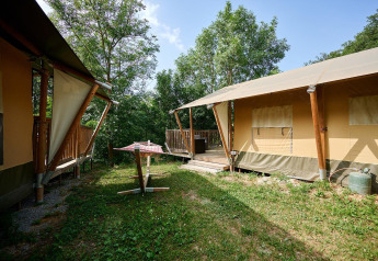 Safari tents with wooden terraces in a green, forested setting at Camping Le Canigou, France.