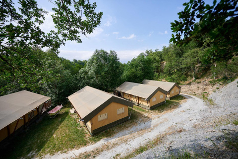 Safari tents called Villatent Nomad at Camping Le Canigou in France, nestled among trees and natural scenery.