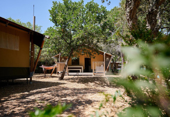 Tienda safari Villatent Nomad en Camping Leï Suves, Francia, rodeada de árboles y una hamaca afuera.