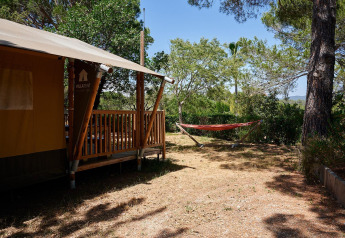 Tienda safari Villatent Nomad con porche y hamaca en un entorno natural en Camping Leï Suves, Francia.