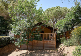 Tienda safari Villatent Nomad en Camping Leï Suves, Francia, rodeada de árboles y vegetación natural.