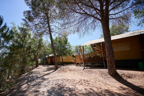 Tienda safari Villatent Nomad en Camping Leï Suves, Francia, rodeada de árboles y naturaleza.