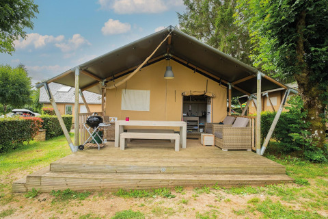 Tienda safari Villatent Nomad con terraza y zona de estar en Camping Les Genêts en Francia.