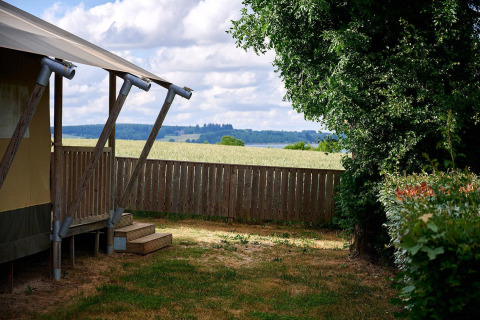 Uitzicht vanuit safaritent Villatent Nomad op Camping Les Genêts in Frankrijk, met houten hek.